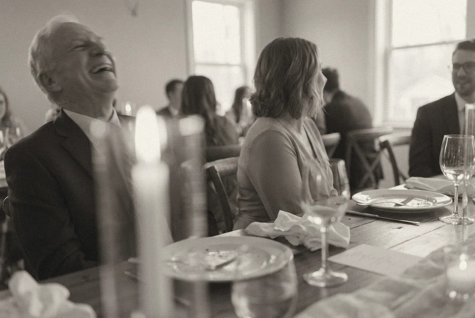 Invitados platicando y riendo en una mesa larga después de la cena